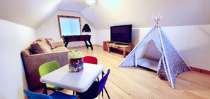 Ett mysigt vardagsrum med en soffa, ett bord med en leksak, en tv och ett tält.
