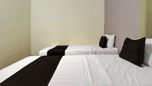 Quarto de hotel com duas camas de solteiro, roupa de cama branca e almofadas de destaque pretas.