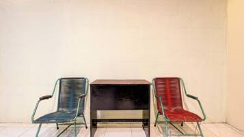 Trois chaises et une table adossées à un mur uni.