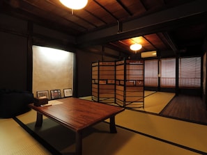 Une pièce de style japonais traditionnel, avec un sol recouvert de tatamis, une basse table en bois et des paravents en papier de riz (shoji).