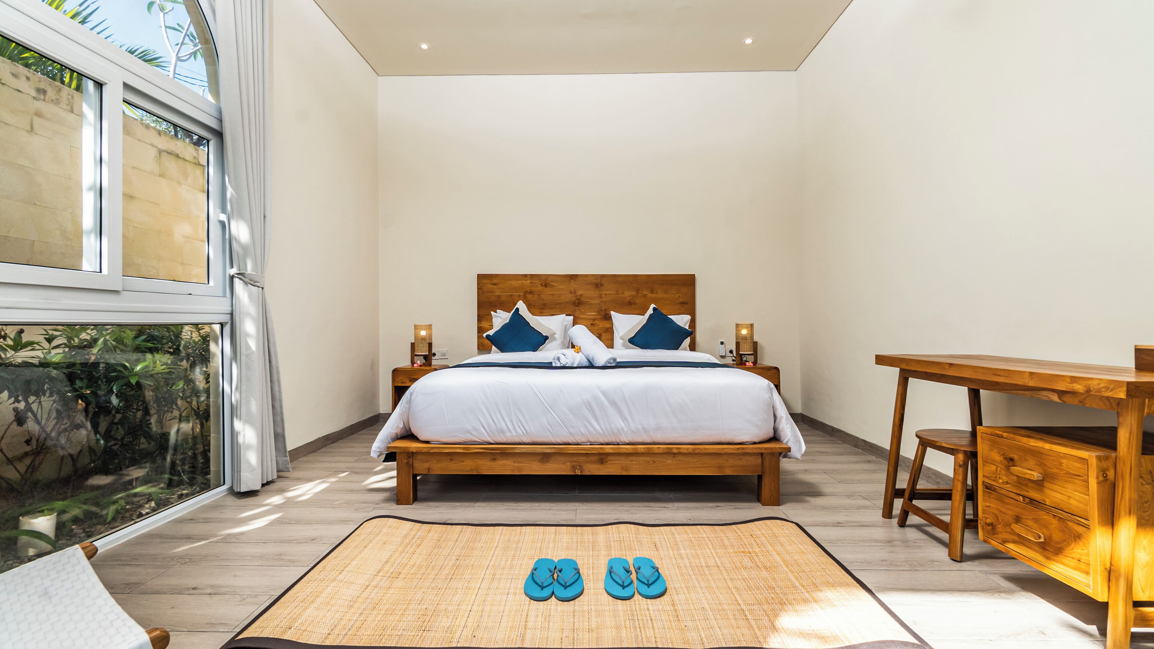 Une chambre moderne avec un lit en bois, une literie blanche et une vue sur la verdure.
