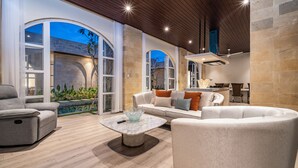 Una sala de estar moderna con sofá, sillones y una mesa de centro de mármol.