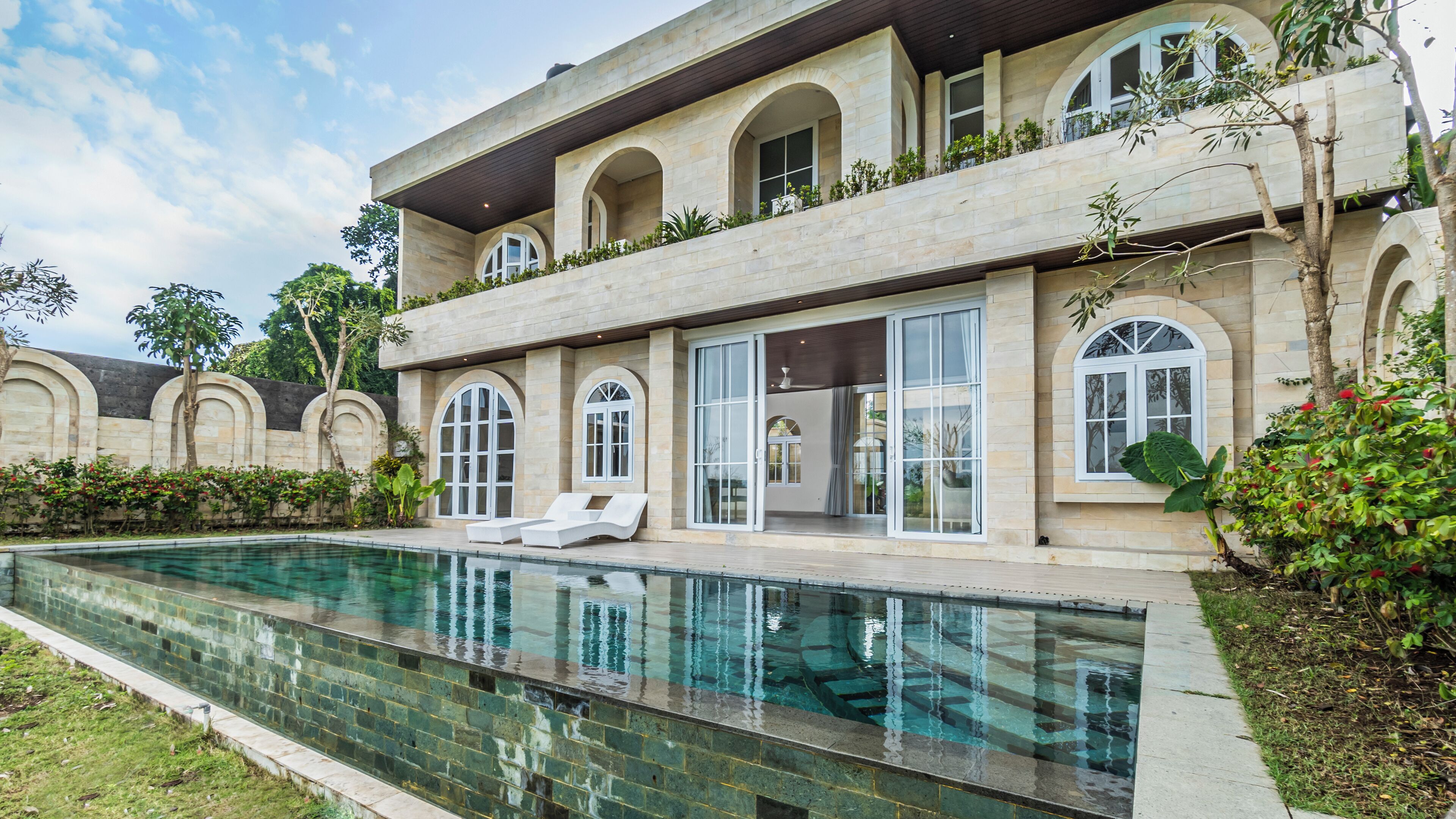 A modern house with a swimming pool, large windows, and a balcony with plants.