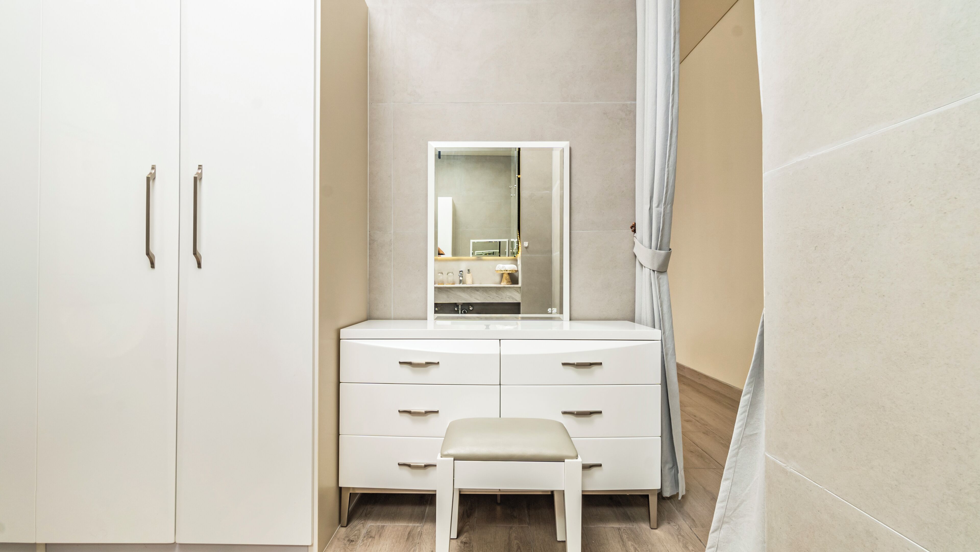 A bathroom with a white vanity, a mirror, and a small stool.