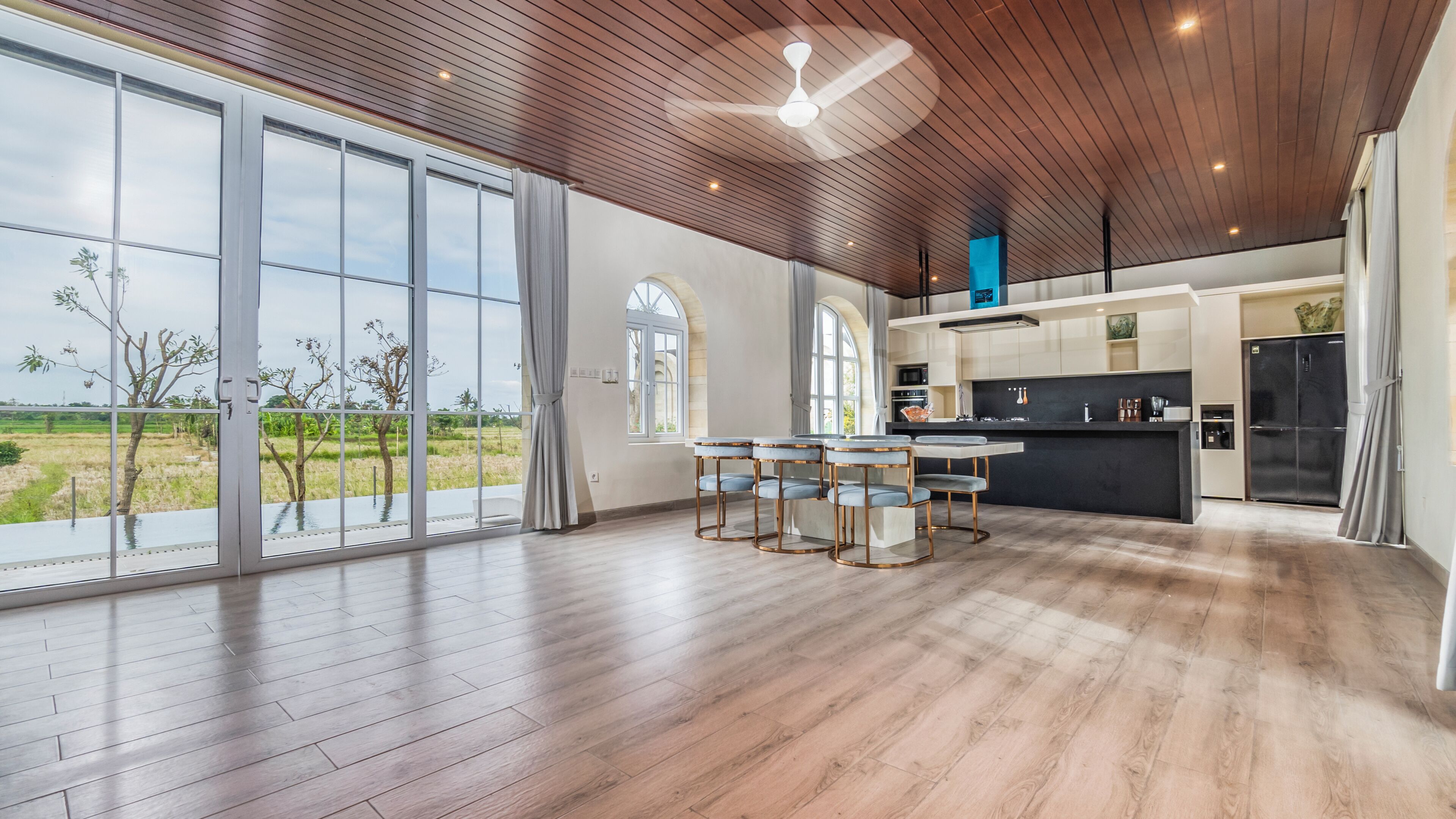 A spacious kitchen with a large island, modern appliances, and a view of a green landscape.