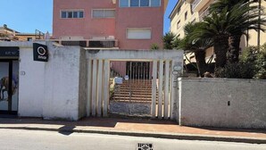 A gated entrance with a metal gate, a sign for 'SNAI,' and a building with balconies in the background. - Casa Carletti - Le Ghiaie (Portoferraio)