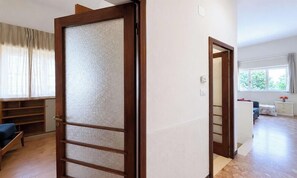 Una habitación con puerta de madera, una cama, una mesita de noche y una ventana con vistas a un jardín.