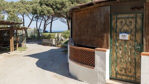Ein Küstenanwesen mit Holztür, überdachter Veranda und Blick auf das Meer.
