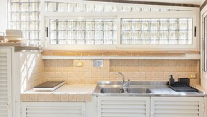 Eine moderne Küche mit Spüle aus Edelstahl, integrierter Waage und einem Fenster mit Jalousien.