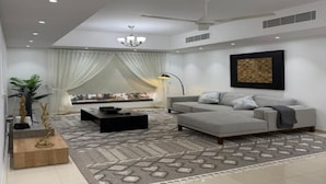 Uma sala de estar moderna com um sofá cinzento, mesa de centro preta e tapete estampado.