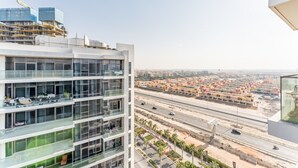 A multi-story building with large windows and balconies, overlooking a busy highway and a residential area. - Contemporary 2BR, Mins. Drive to Butterfly Garden (Dubai)