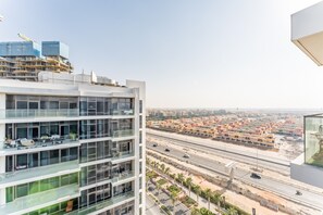 A multi-story building with large windows and balconies, overlooking a busy highway and a residential area. - Contemporary 2BR, Mins. Drive to Butterfly Garden (Dubai)