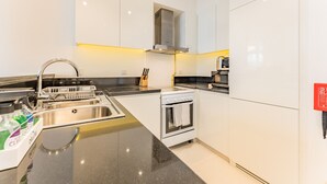 Eine moderne Küche mit Spüle aus Edelstahl, einem eingebauten Backofen und einer schwarzen Arbeitsplatte.