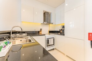 Eine moderne Küche mit Spüle aus Edelstahl, einem eingebauten Backofen und einer schwarzen Arbeitsplatte.