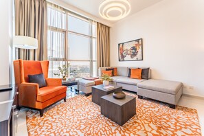 Ein modernes Wohnzimmer mit großem Fenster, einer Couch, einem Sessel, einem Couchtisch und einem Gemälde an der Wand.