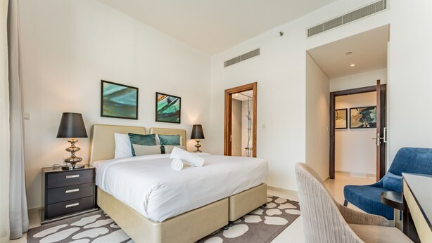Ein Hotelzimmer mit einem Bett, einem Schreibtisch, einem Stuhl und Kunstwerken an den Wänden.