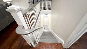 Un escalier avec des balustrades blanches et une main courante en bois menant à un palier.