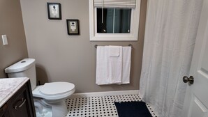 Une salle de bain équipée de toilettes, d’un porte-serviettes, d’une fenêtre et d’un rideau de douche.
