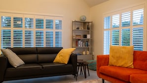 Ein Wohnzimmer mit einer schwarzen und einer orangefarbenen Couch, einem kleinen Tisch und einem Bücherregal.