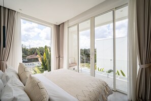 Una camera da letto con un grande letto, vista sull'esterno e una porta scorrevole in vetro.