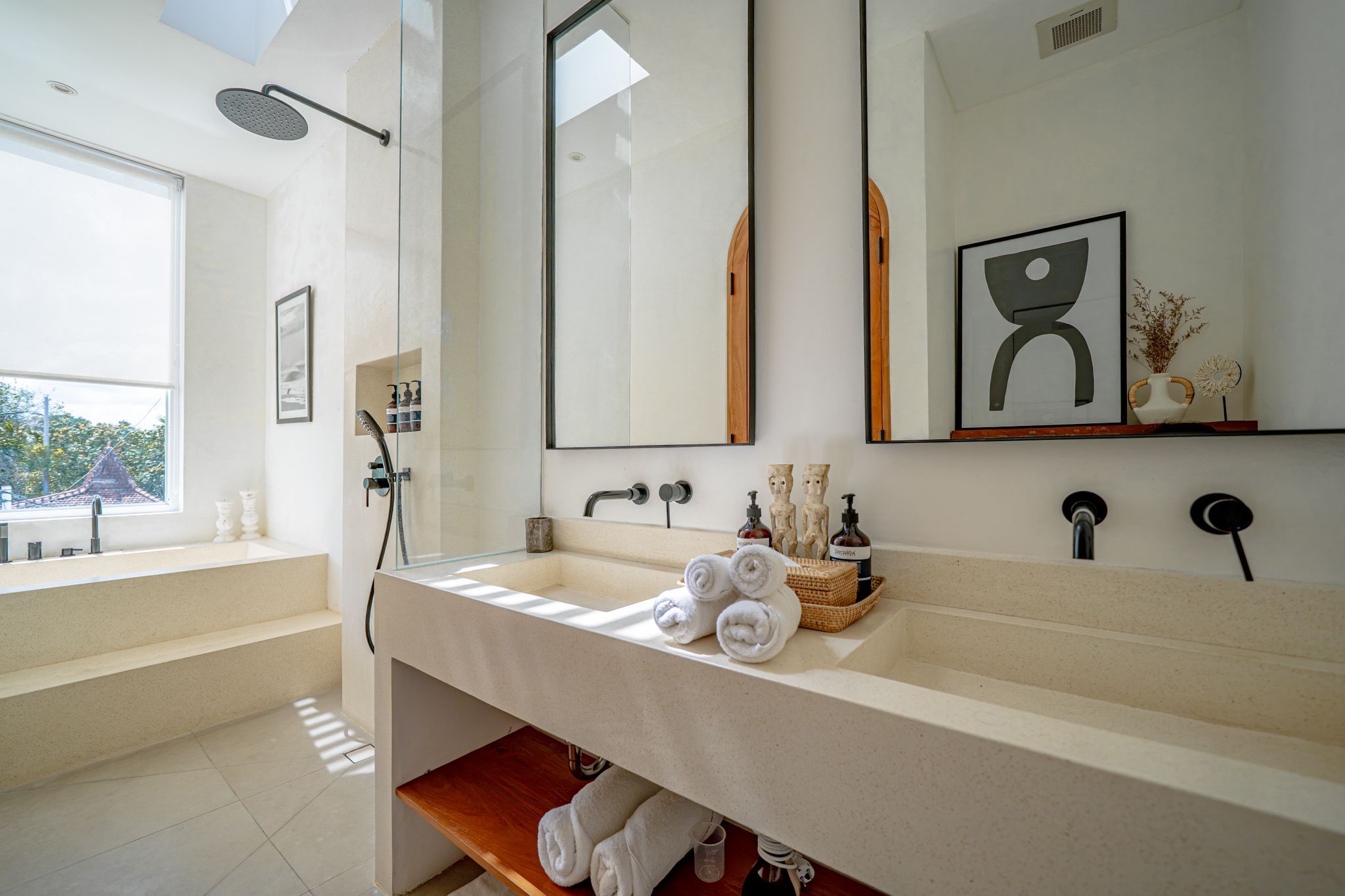 Un baño moderno con un espejo grande, una ducha y un lavabo con toallas.