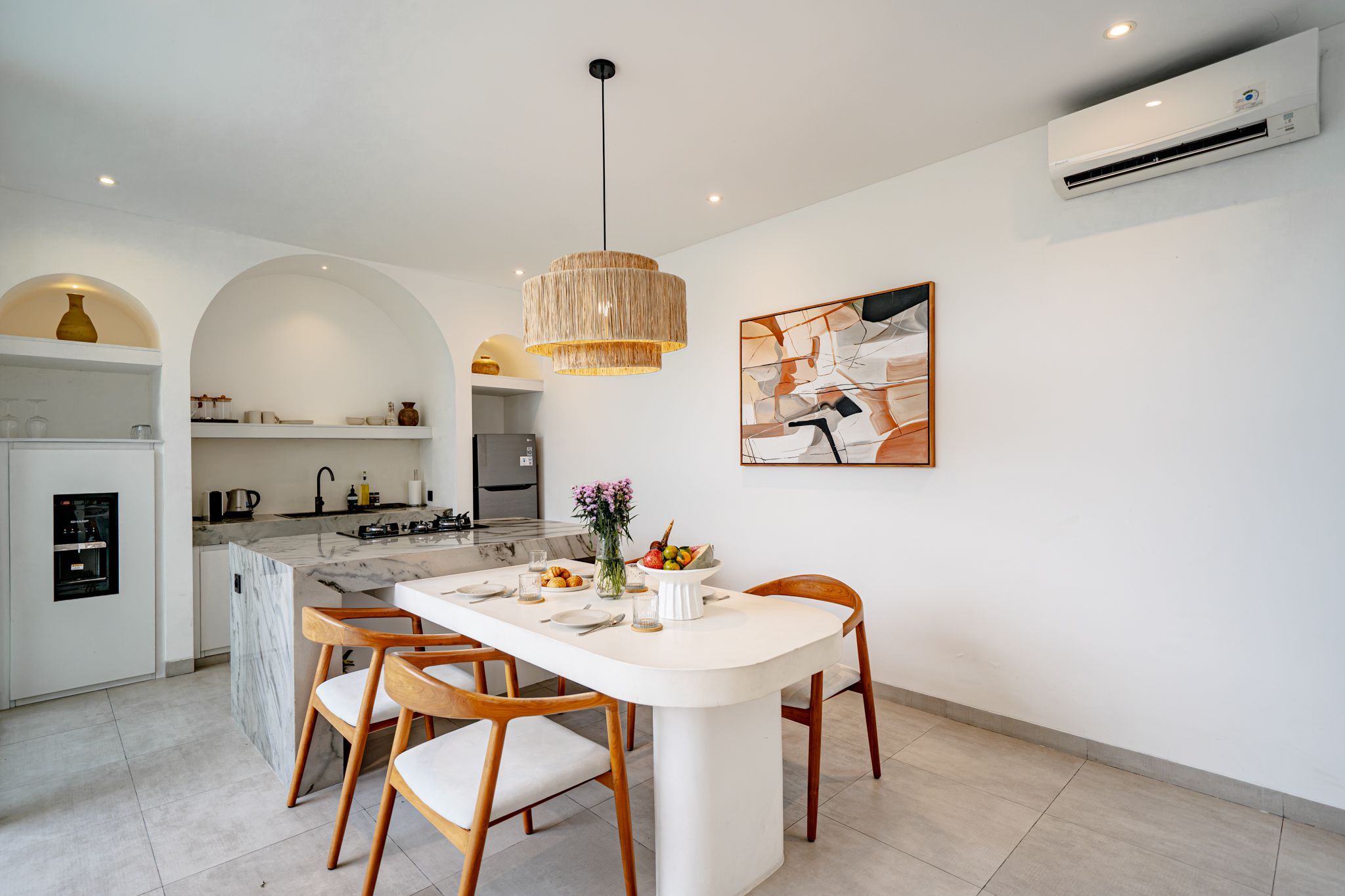 A modern kitchen with a marble countertop, a built-in oven, and a stainless steel refrigerator.