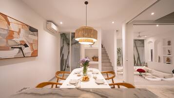 Un comedor moderno con una mesa de mármol, sillas de madera y una lámpara colgante.