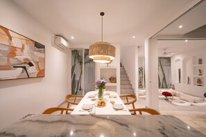 Un'area pranzo moderna con tavolo in marmo, sedie di legno e lampadario.