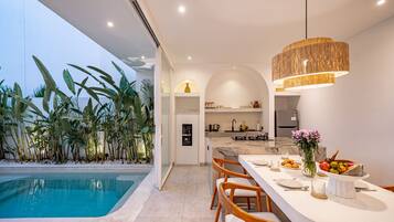 A modern kitchen with a marble countertop, a built-in oven, and a stainless steel refrigerator.