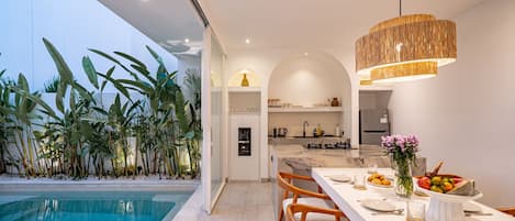 A modern kitchen with a marble countertop, a built-in oven, and a stainless steel refrigerator.