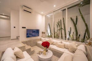 A modern living room with a sofa, coffee table, and a flat-screen TV. - The Belluoccio Villa (Canggu)