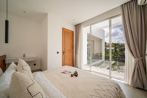 Een moderne slaapkamer met een groot bed, een nachtkastje, een kledingkast en een schuifdeur naar een balkon.