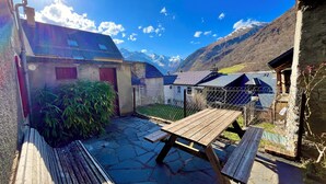 En innergård med en träbänk, ett picknickbord och en liten byggnad med en röd dörr.