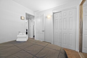 Ein Schlafzimmer mit einem Bett, einer weißen Tür und einem Flur, der zu einem anderen Raum führt.
