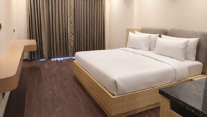 Moderni hotellihuone, jossa on puinen sängynrunko, puinen työpöytä ja tumma puulattia.