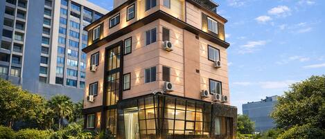 A multi-story hotel with a modern design, featuring large windows and air conditioning units.