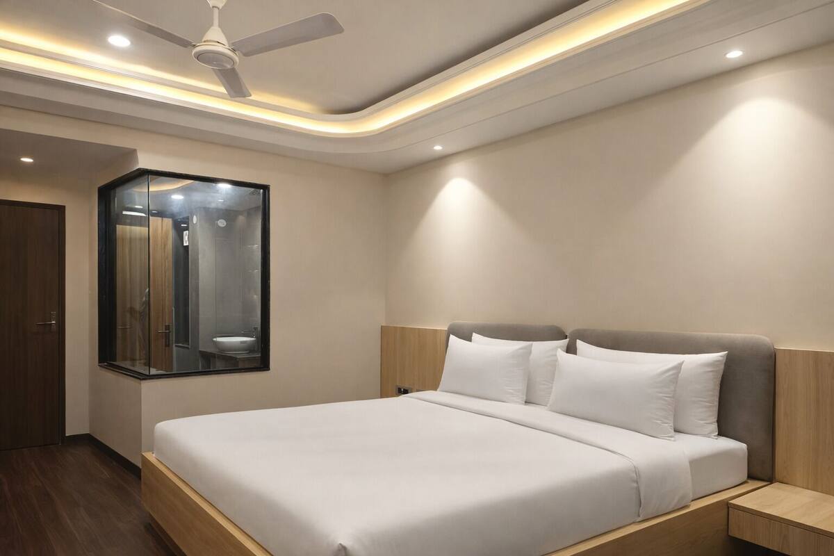 A modern hotel room with a large bed, a ceiling fan, and a mirror reflecting the bathroom.