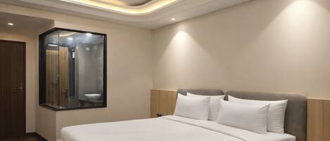 A modern hotel room with a large bed, a ceiling fan, and a mirror reflecting the bathroom.