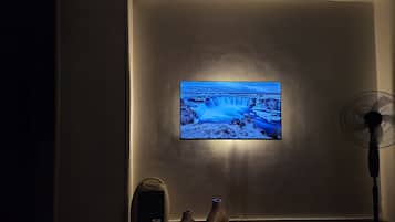 A room with a large flat-screen TV mounted on the wall displaying a waterfall scene.
