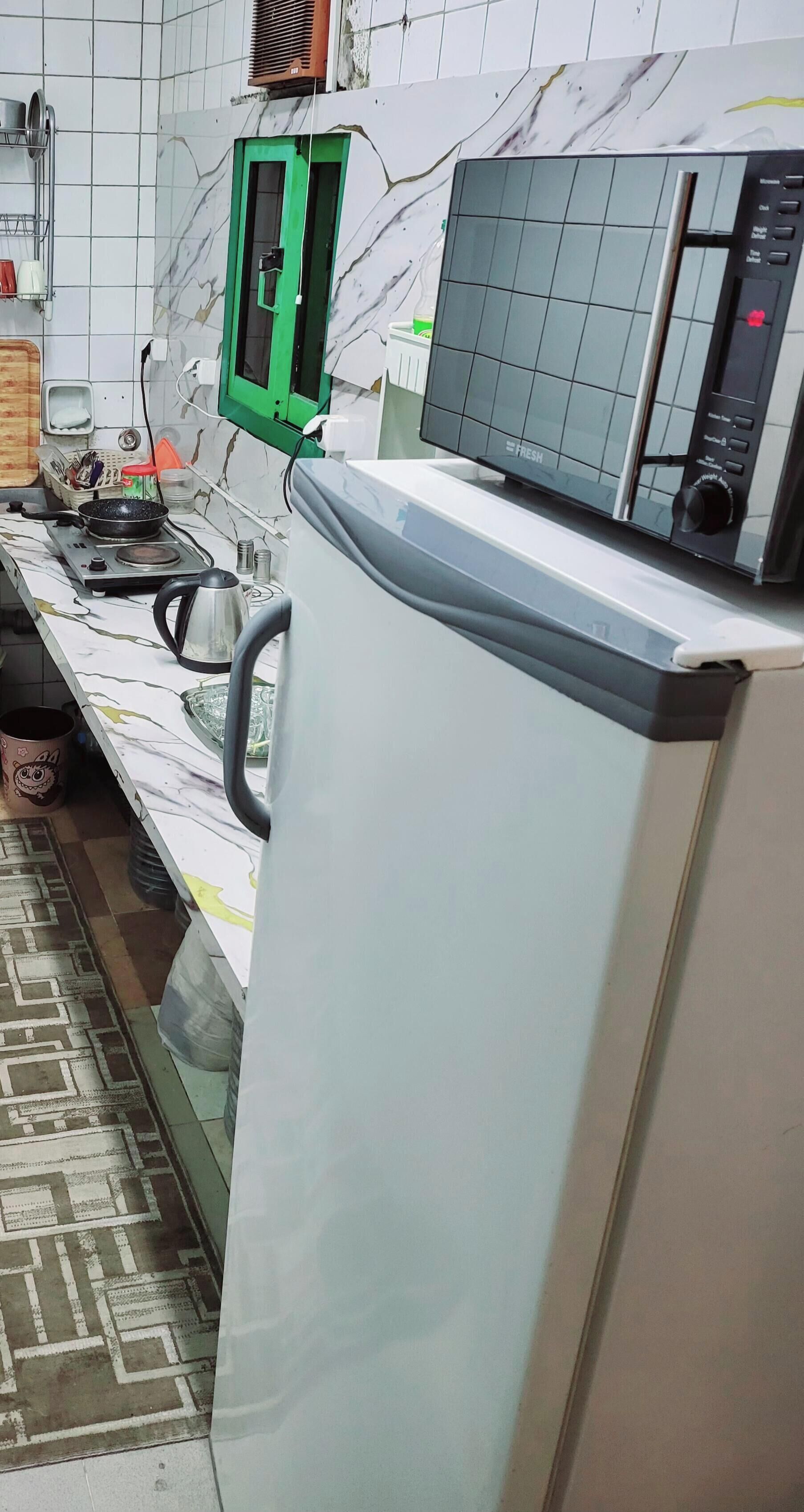 A kitchen with a microwave, a kettle, and a stove.