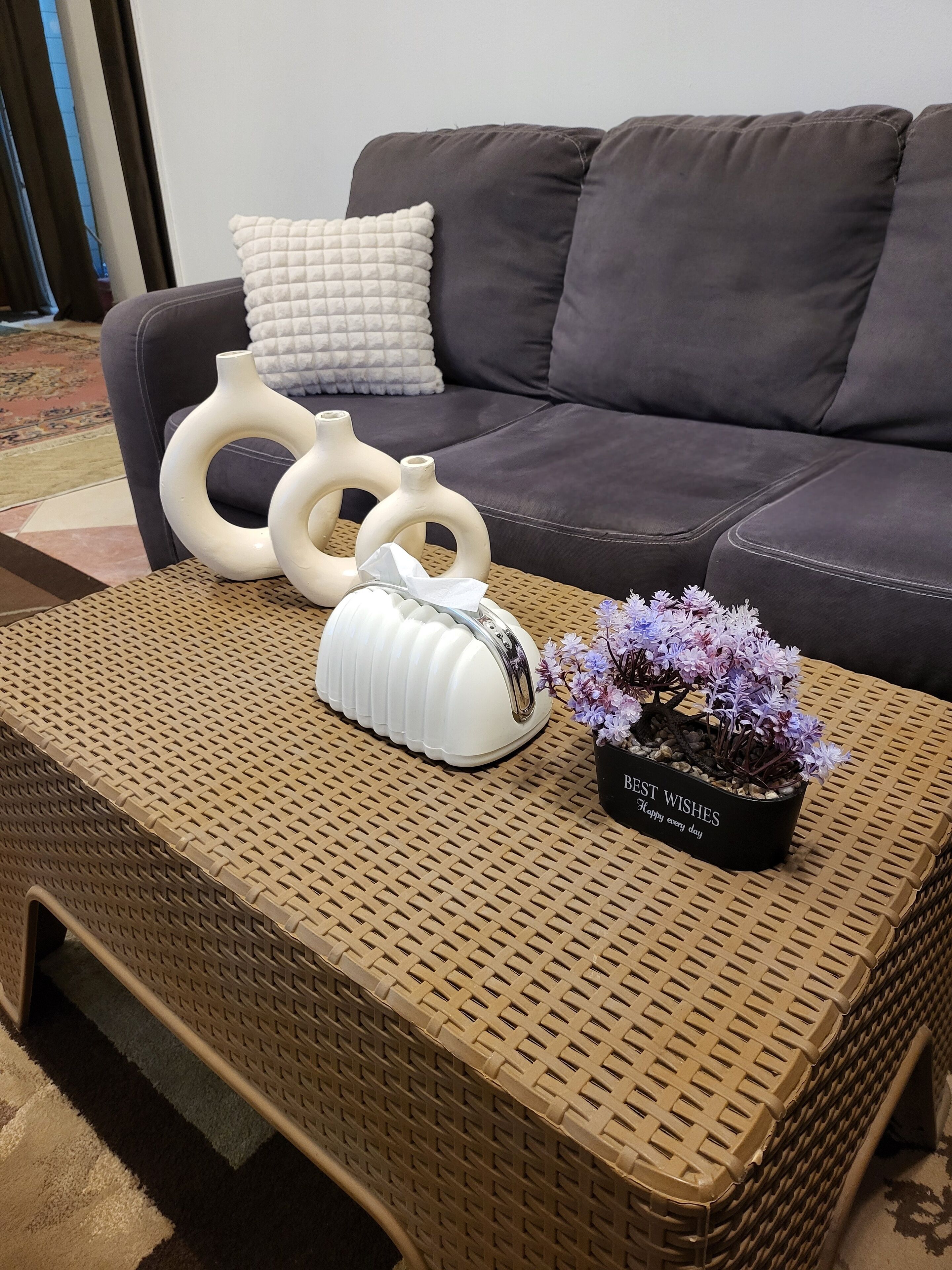 A wicker coffee table with a potted plant and decorative vases.