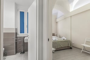 A hotel room with a bed, a chair, a sink, and a window. - Garibaldi (Loano)