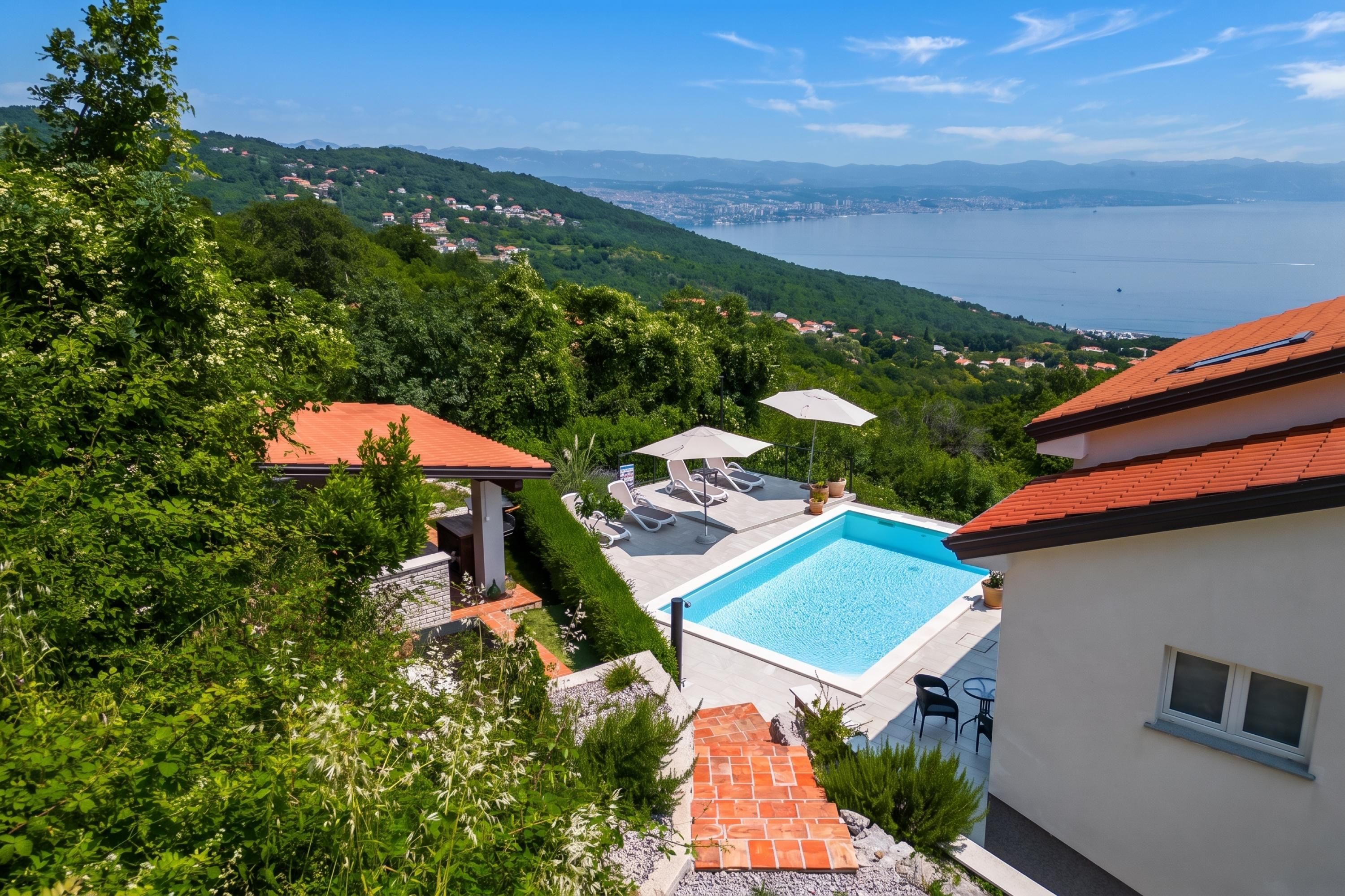 Una propietat residencial amb piscina, mobiliari exterior i vistes a un llac i muntanyes llunyanes.