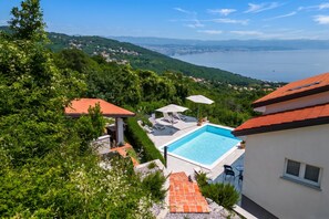 A residential property with a swimming pool, outdoor seating, and a view of a lake and distant mountains. - Panoramic Holiday Home Kvarner: Pool & Sea View (Opatija)