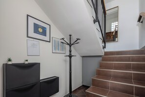 Un escalier recouvert de carreaux bruns, un lampadaire noir et des certificats encadrés accrochés au mur.