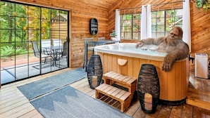 Ein Holzblockhaus-Innenraum mit Whirlpool, Holzbanken und einer Essecke.