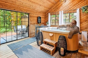 A wooden cabin interior with a hot tub, wooden benches, and a dining area. - Forest Hideaway with Hot Tub, Custom Fire-Pit, BBQ Deck & Cozy Mountain Vibes, Minutes to Mountain (Mount Hood Village)