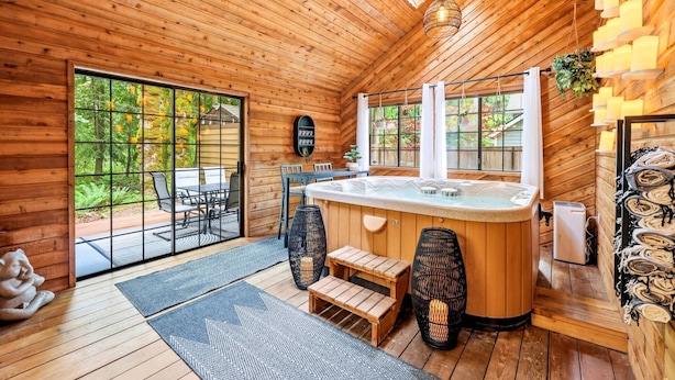 Ein Holzblock-Interieur mit Whirlpool, Sitzgruppe und großen Fenstern.