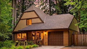 Ein zweistöckiges Haus mit Garage, umgeben von dichtem Wald.