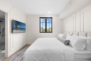 Un dormitorio con cama, ventana, un cuadro y zona de ducha.